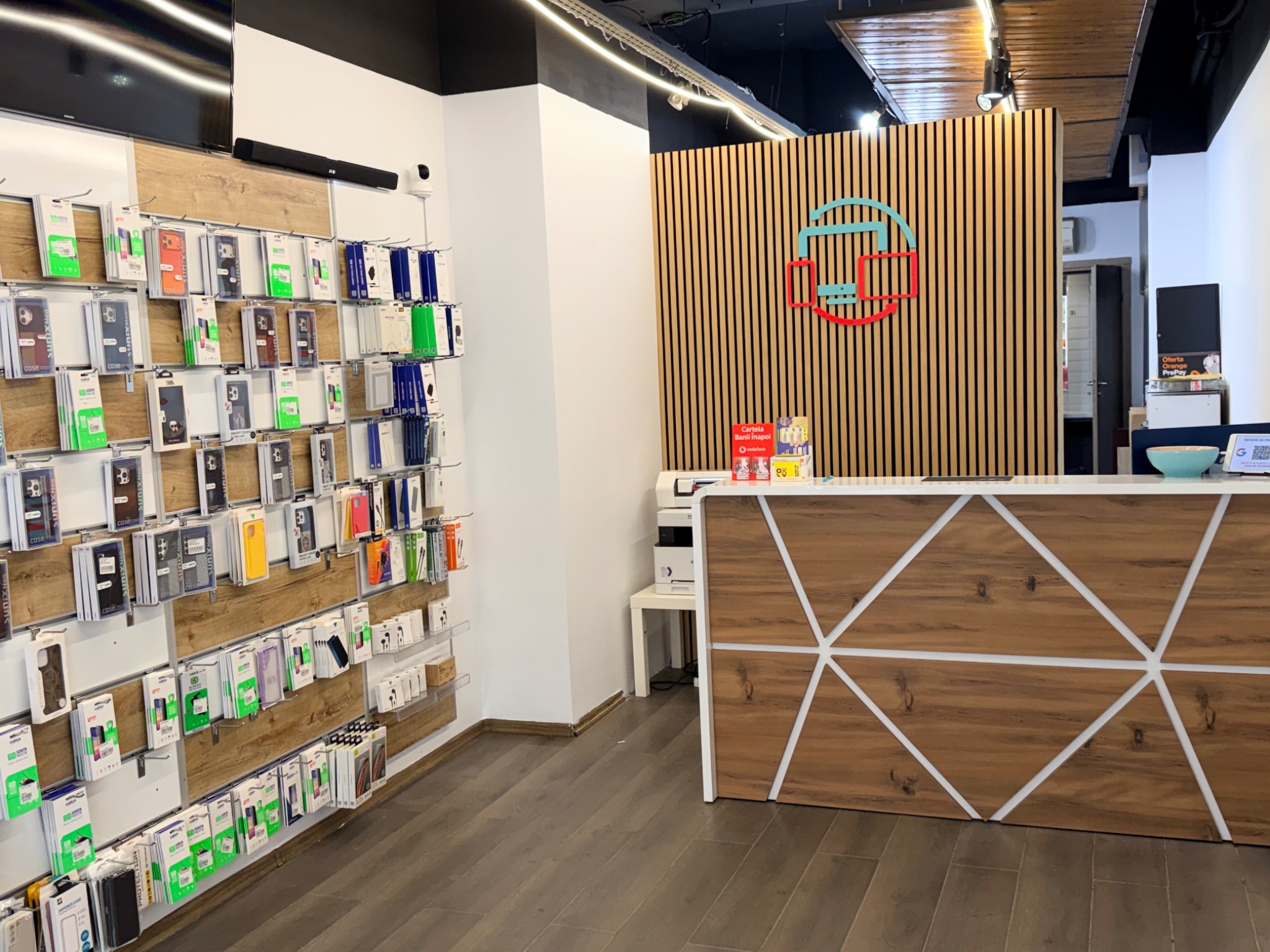 Recepția magazinului Device Center din București, cu sigla roșie și turcoaz și zona de accesorii