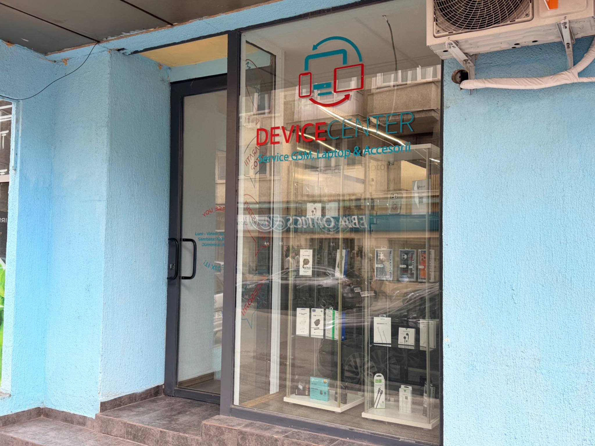 Intrarea în magazinul Device Center, cu sigla pe vitrină și ușa de acces